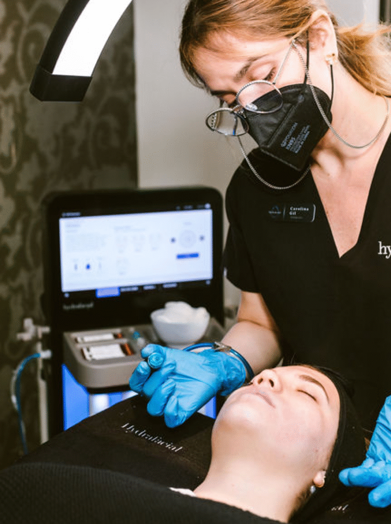 Licensed aesthetician performing a HydraFacial treatment on a client.